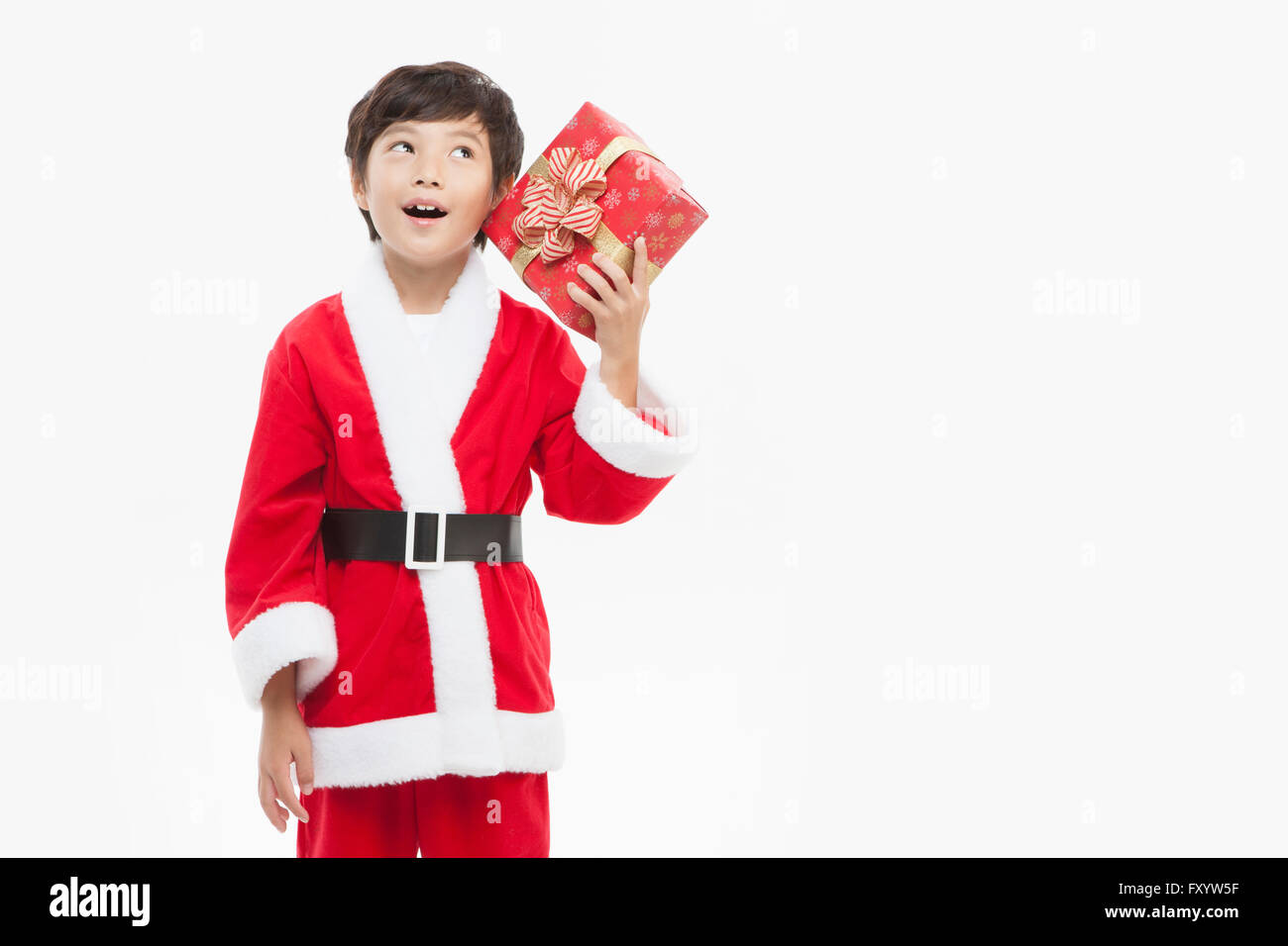 Smiling boy in Santa's clothes holding présente un fort looking up Banque D'Images