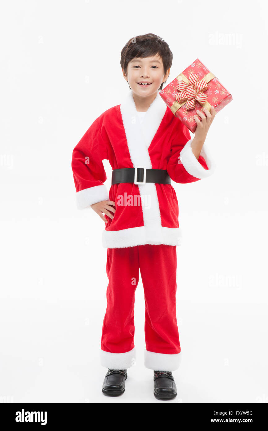 Smiling boy in Santa's clothes holding un présent avec une main sur sa taille fixant à l'avant Banque D'Images