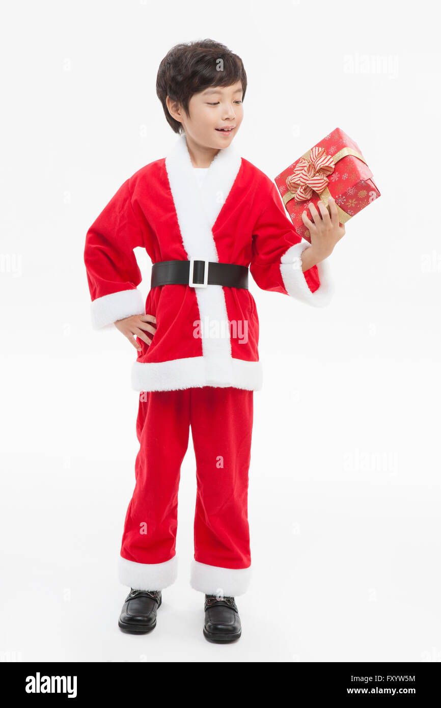Smiling boy in Santa's clothes holding présente un fort avec une main sur sa taille à la bas Banque D'Images