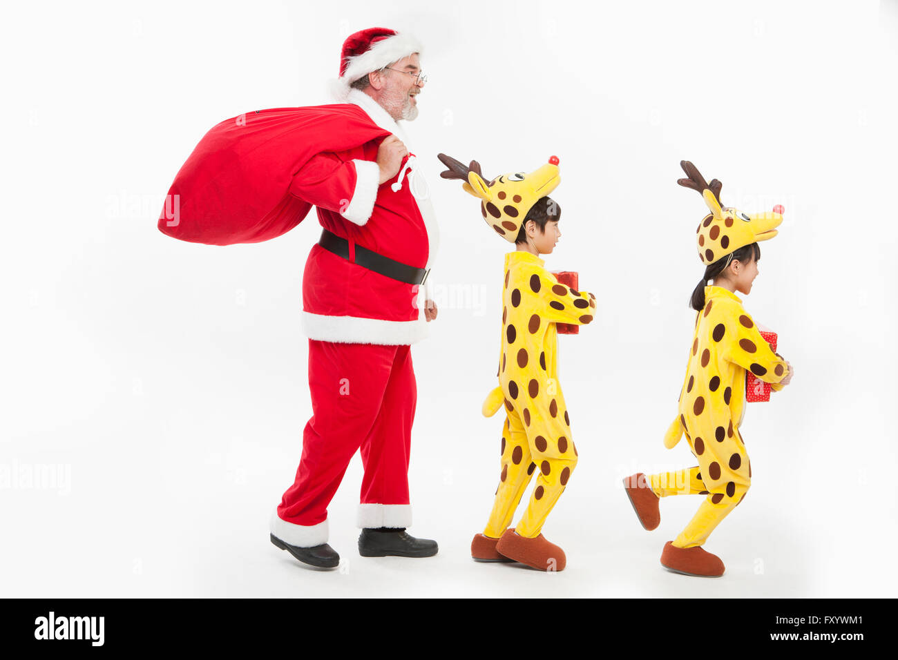 Vue latérale du smiling Santa et les enfants habillés comme des balades avec des rennes présente Banque D'Images