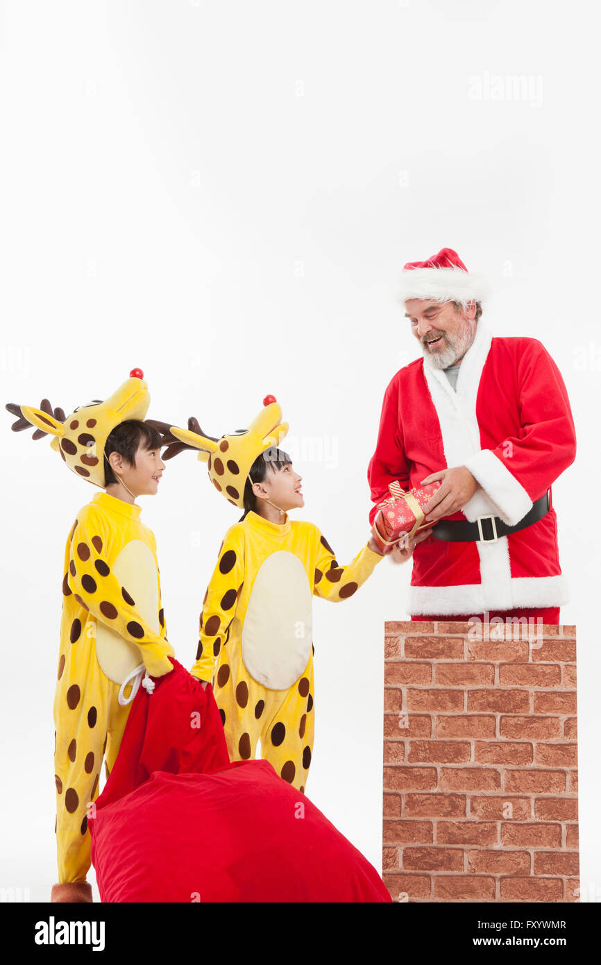 Enfants habillés comme donnant un renne présent fort de Santa chimney Banque D'Images
