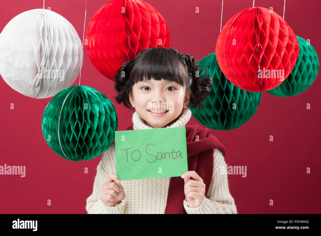 Portrait of smiling girl holding a carte pour père Noël avec des décorations de Noël à regarder/ Banque D'Images