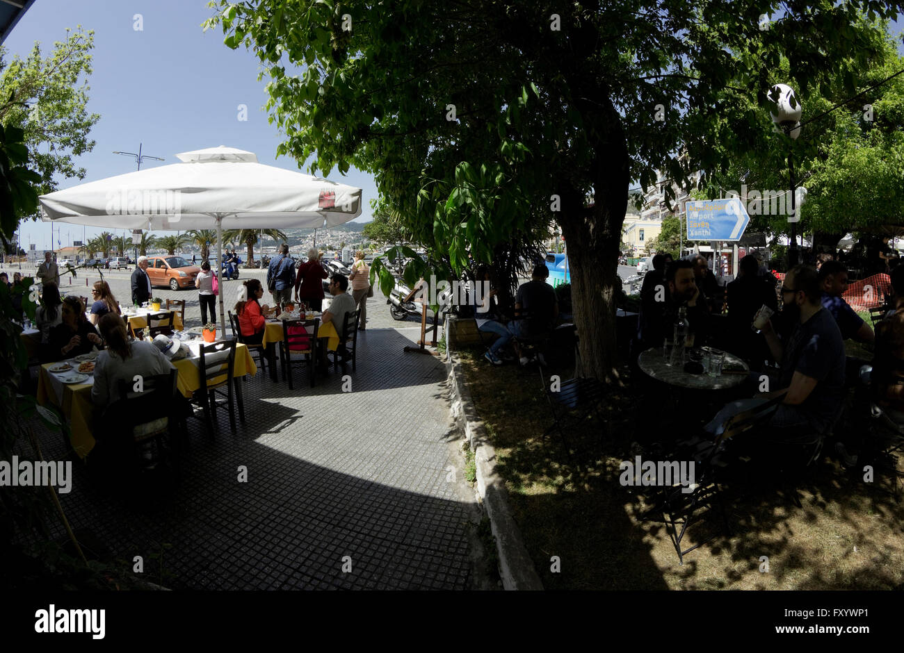 Café grec magasins bondés de gens profitant des boissons dans l'ombre des arbres de Karaoli square (plateia) passerelle. Kavala, Grèce Banque D'Images