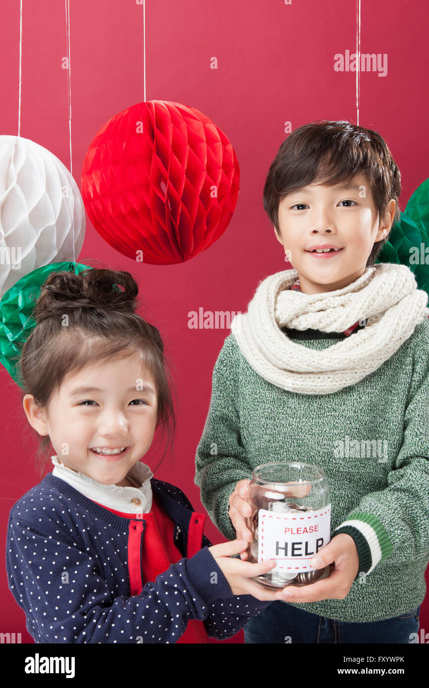 Portrait of smiling boy and girl holding une collection fort avec des ornements de Noël fixant à l'avant Banque D'Images