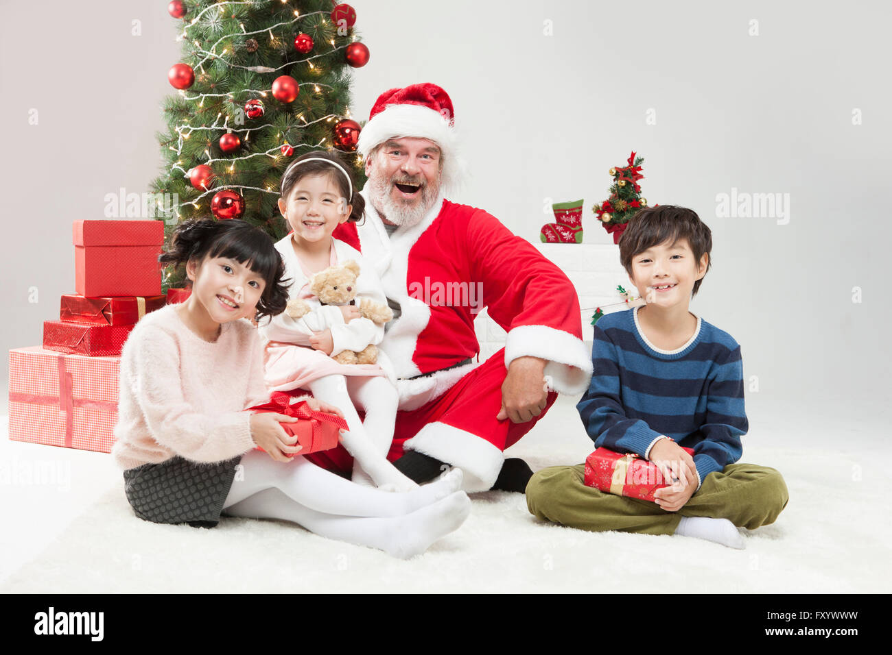 Smiling Children et souriant Santa avec boîtes présent assis regardant à l'avant Banque D'Images