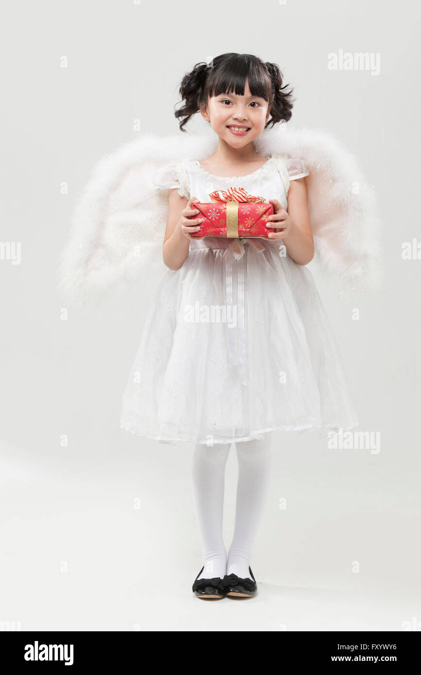 Smiling girl habillé comme un ange debout avec un présent fort Banque D'Images