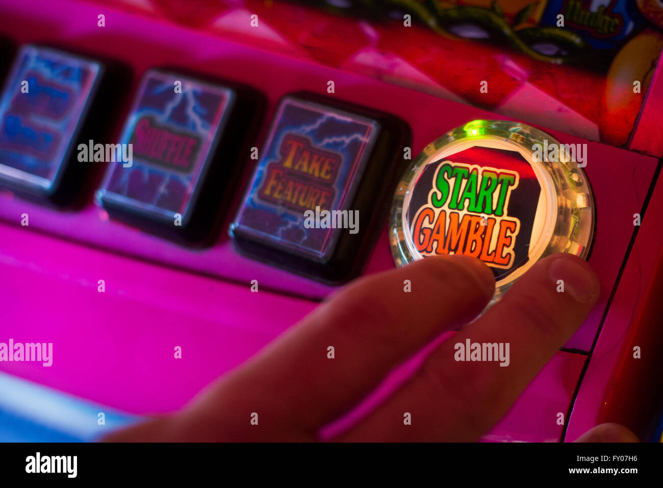 La main d'un homme sur le point d'appuyer sur le bouton start gamble sur une machine de fruit Banque D'Images