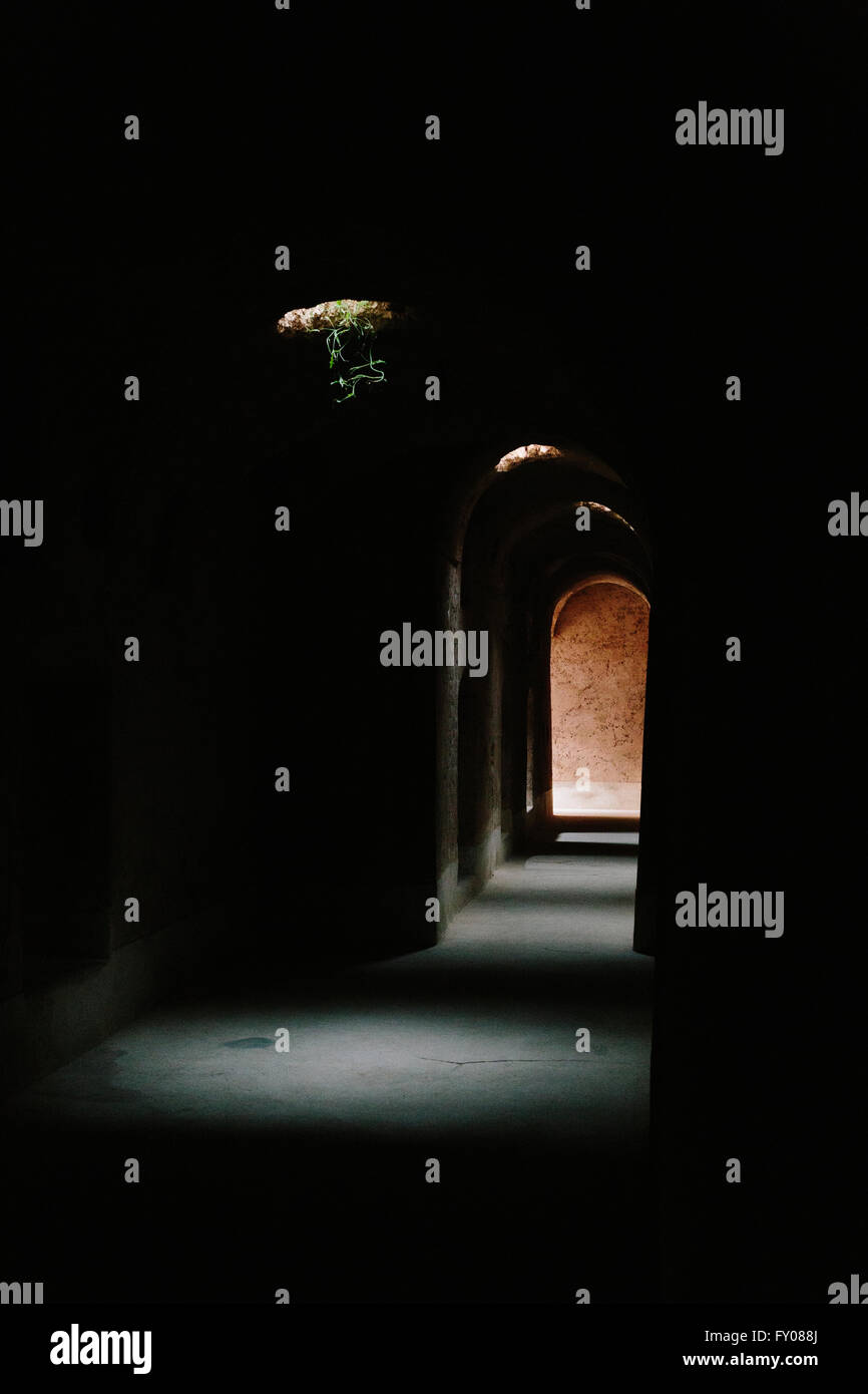 La lumière au bout du tunnel. Faisceaux de lumière percer un tunnel sombre dans le parc du Palais Royal de Marrakech. Banque D'Images La lumière au bout du tunnel. Faisceaux de lumière percer un tunnel sombre dans le parc du Palais Royal de Marrakech. Banque D'Images