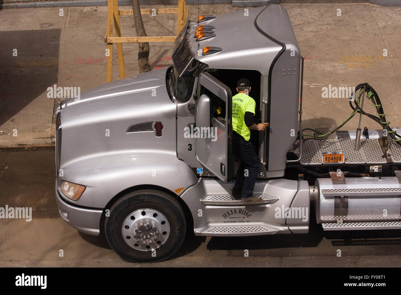 Chauffeur de camion de l'opérateur propriétaire debout à la porte ouverte d'un gros camion Kenworth semi-remorques stationnés sur une rue de la ville Banque D'Images