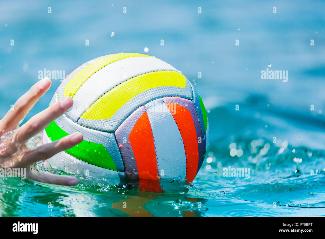 Une main d'un nageur atteint pour un ballon de plage dans l'eau Banque D'Images