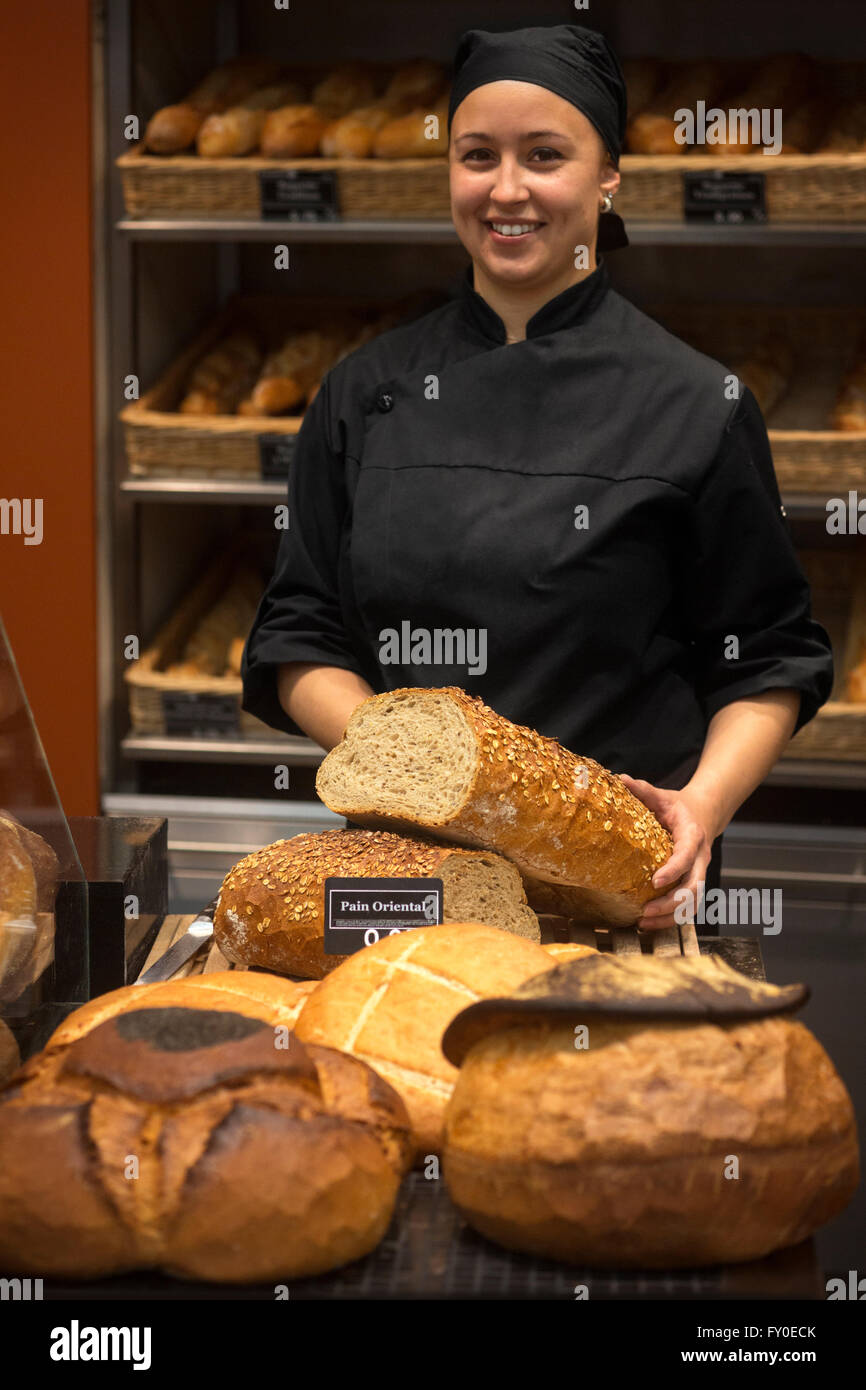 A smiling femme du boulanger présentant son loafs de pain. Vendeuse en  boulangerie uniforme noir holding miche de pain Photo Stock - Alamy