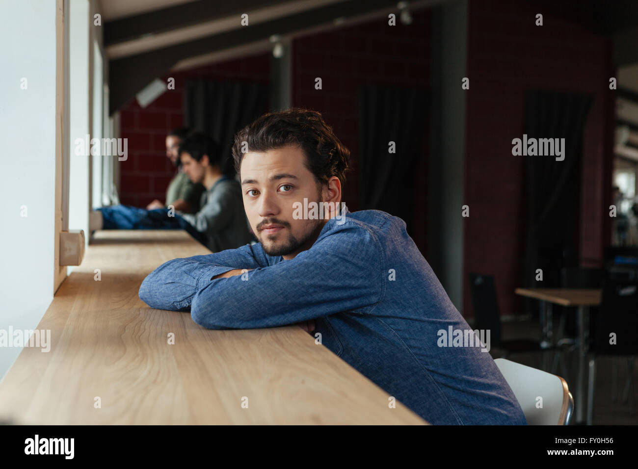 L'homme assis à la table et looking at camera Banque D'Images