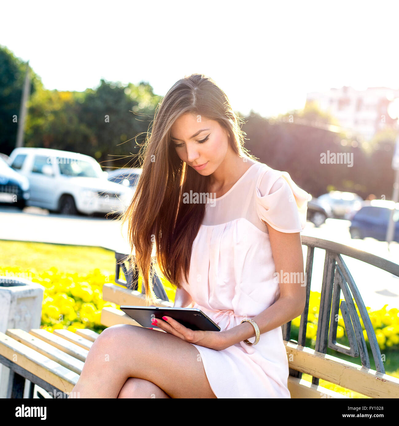 Beautiful Girl holding tablet, journée ensoleillée, sur un banc, le modèle de mode de vie urbaine. Lire des e-books, réseaux sociaux assis Banque D'Images