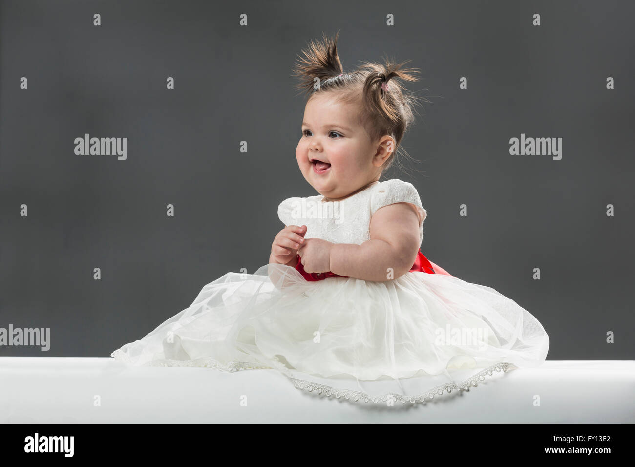 Cute baby girl wearing dress contre l'arrière-plan gris Banque D'Images