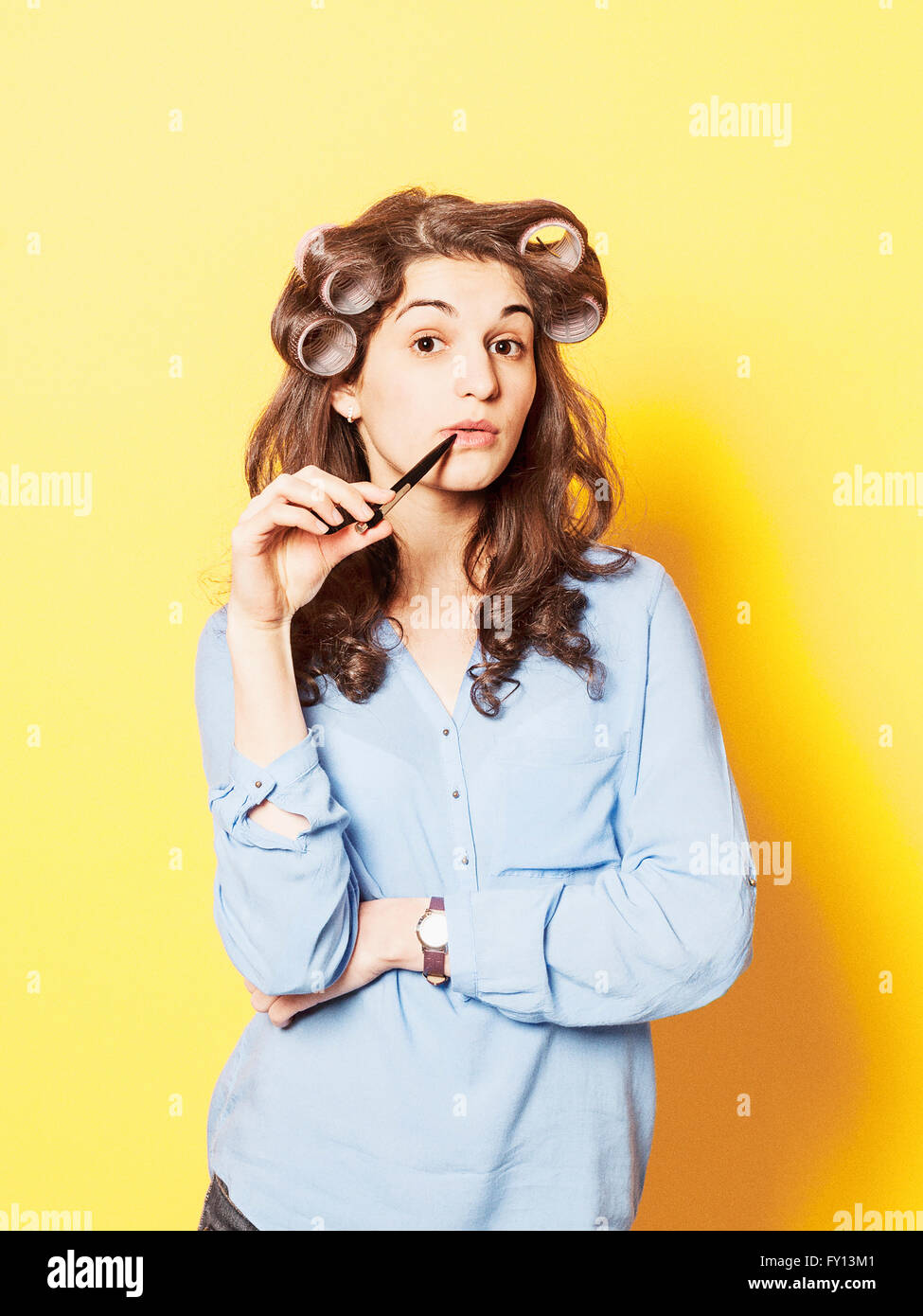 Portrait of young woman wearing hair curlers contre fond jaune Banque D'Images