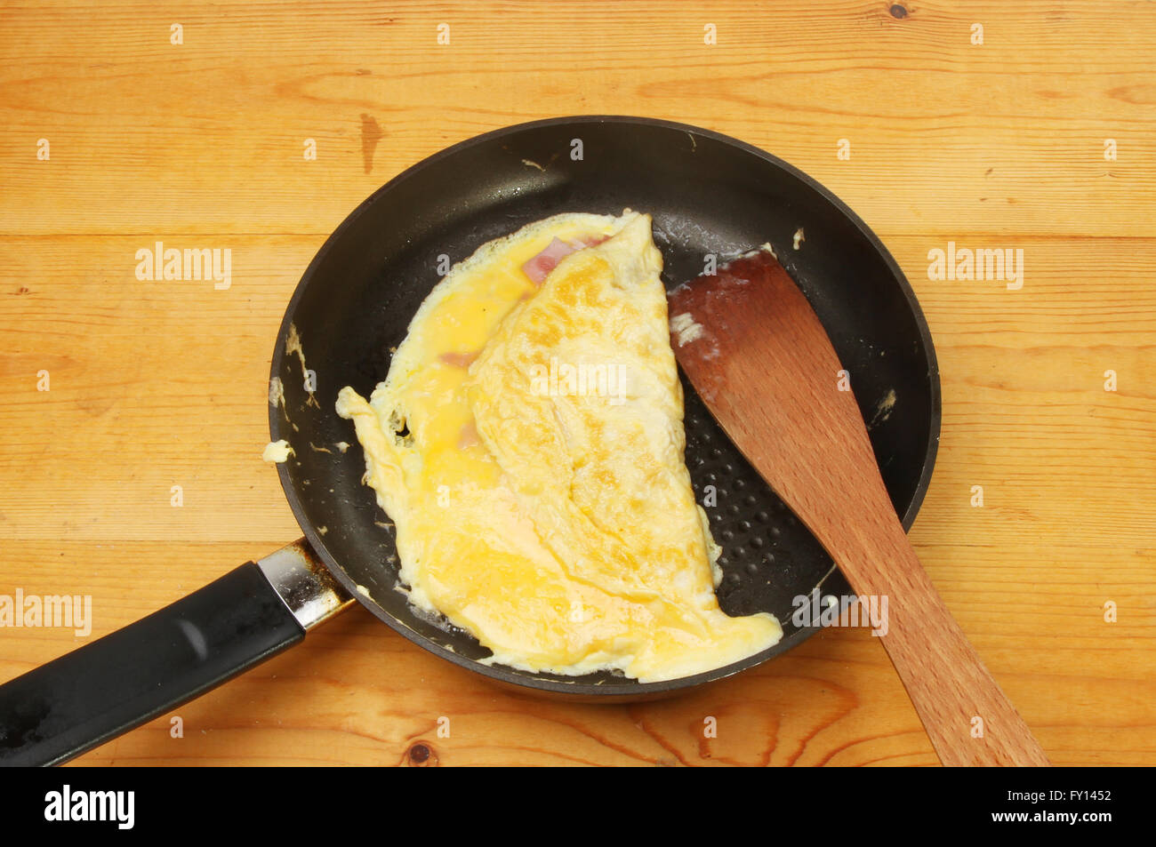 Fromage et Jambon omelette dans une poêle avec une spatule en bois sur un plan de travail de cuisine Banque D'Images