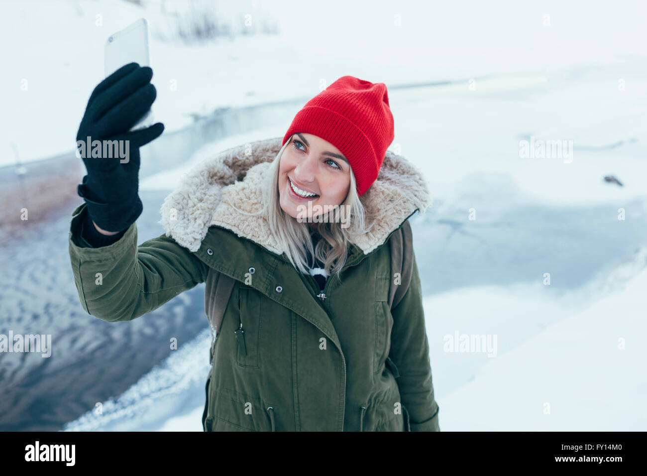 Happy young woman on smart phone selfies en hiver Banque D'Images