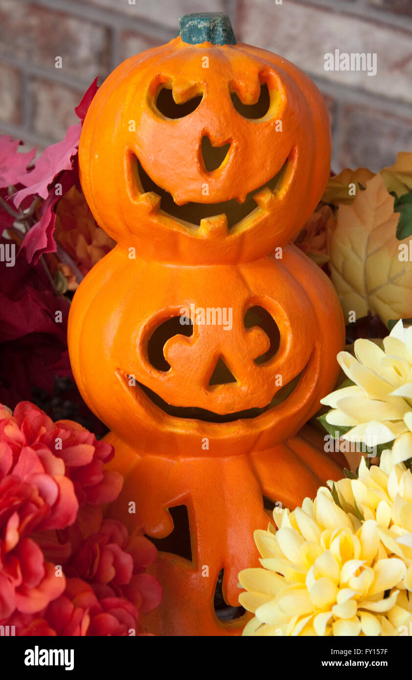Une décoration de 3 stacked jack-o-lanternes entourée de fleurs Banque D'Images Une décoration de 3 stacked jack-o-lanternes entourée de fleurs Banque D'Images