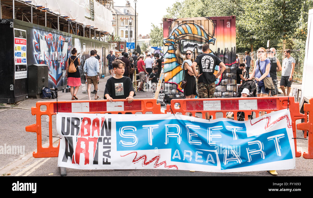 Jeune garçon en face d'un grand panneau publicitaire la promotion de l'Art Urbain Street Festival a lieu chaque année dans les rues de Brixton. Banque D'Images