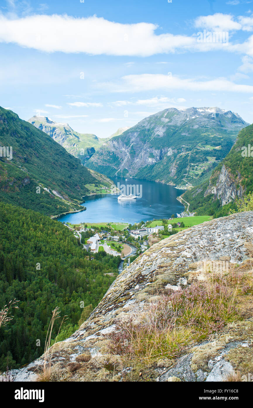 Grand bateau de croisière naviguant dans un fjord norvégien entouré de montagnes et d'une vallée verte avec village Banque D'Images