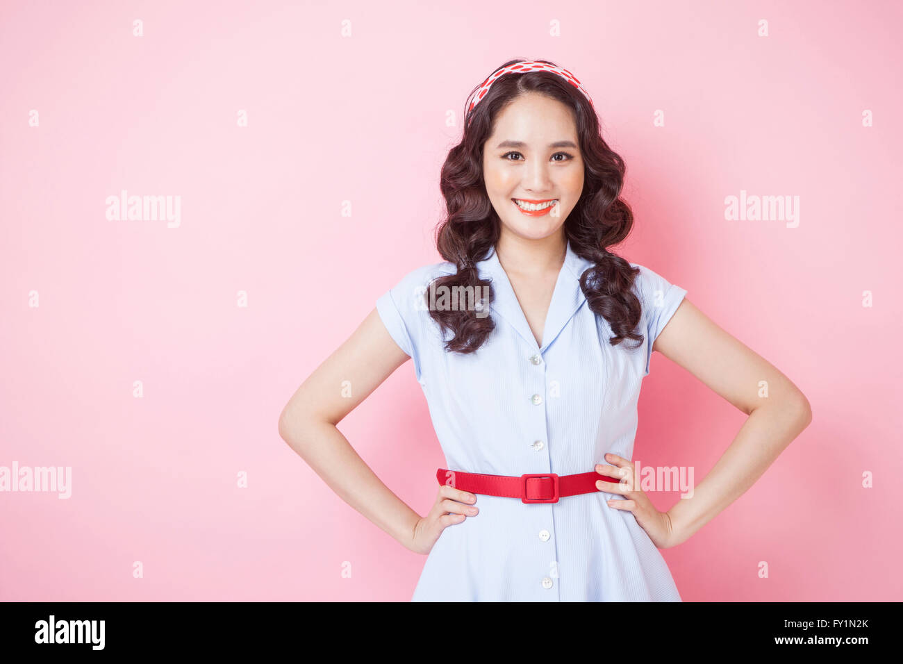 Portrait of young smiling woman style rétro en plaçant ses mains sur ses reins fixant à l'avant Banque D'Images