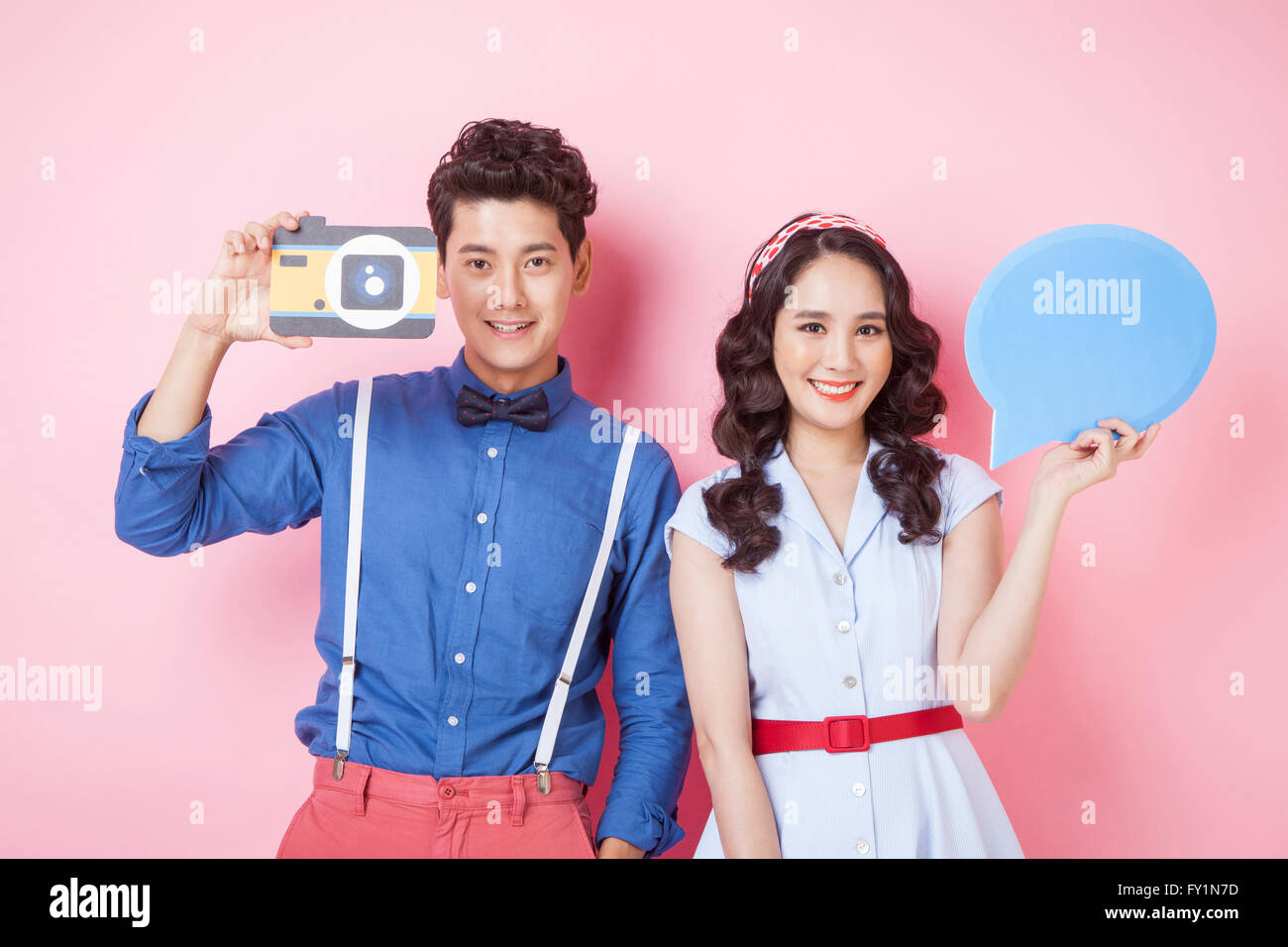 Portrait of young smiling couple in styles retro montrant caméra et bulle à regarder/ Banque D'Images
