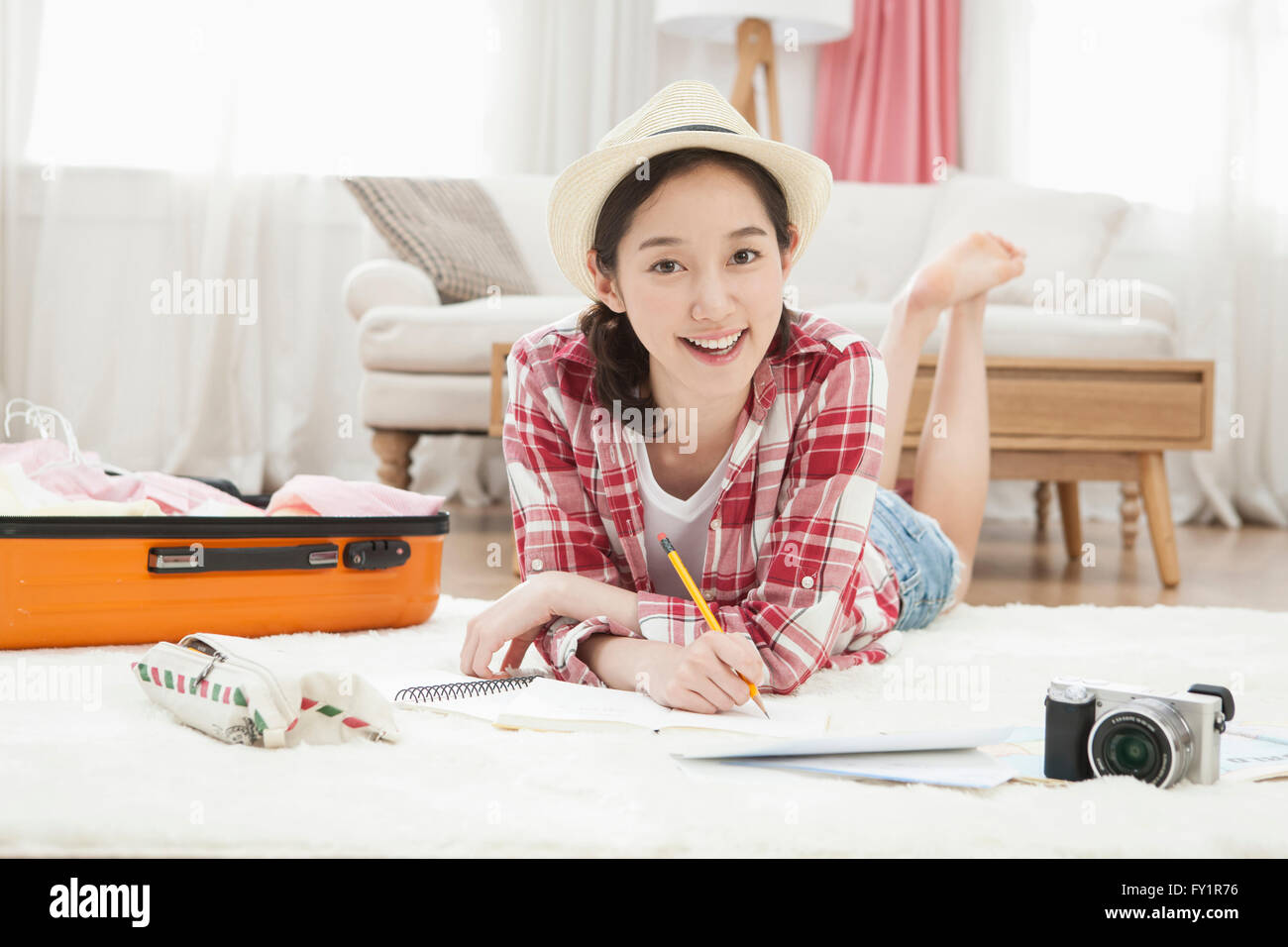 Young smiling woman lying face vers le bas et l'écriture fixant à l'avant avec le transporteur et de l'appareil photo Banque D'Images