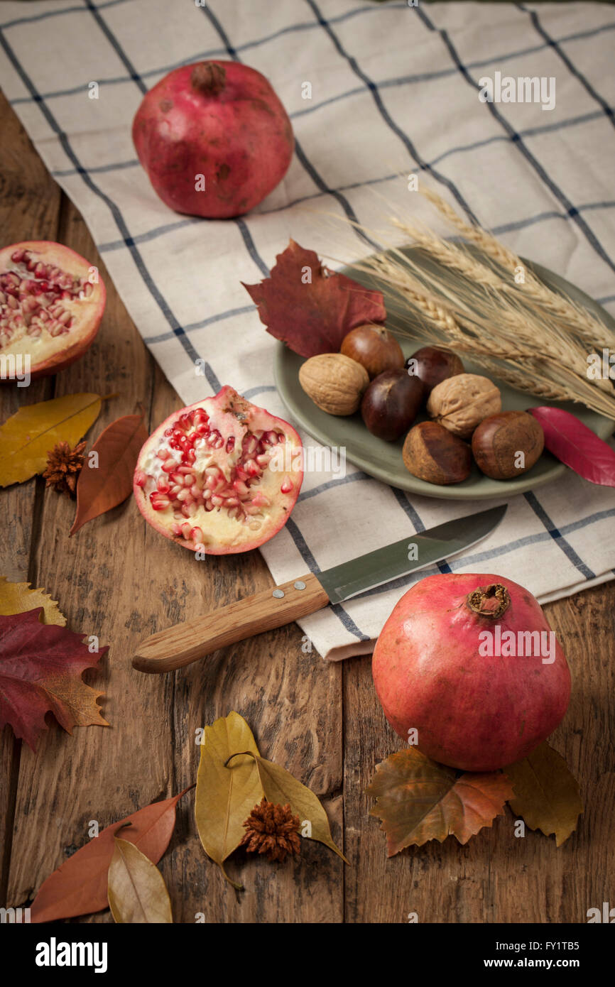 Des produits de la ferme, tels que les grenades, les noix et le riz avec un couteau et les feuilles tombées sur la table Banque D'Images