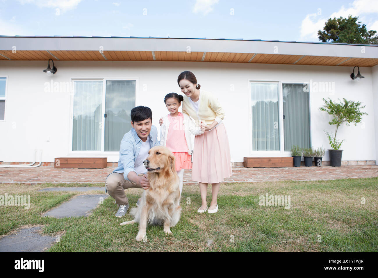 Famille avec un chien de compagnie à la cour de leur maison à Jeju représentant la vie rurale Banque D'Images