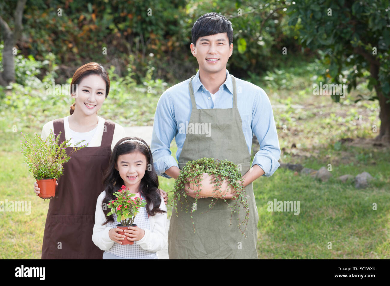 Fille et ses parents tenant une plante en pot sur le chantier chaque représentant de l'horticulture et de la vie rurale Banque D'Images