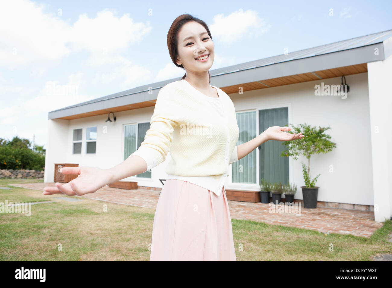 Femme avec ses bras ouverts à la cour d'une maison représentant la vie rurale Banque D'Images