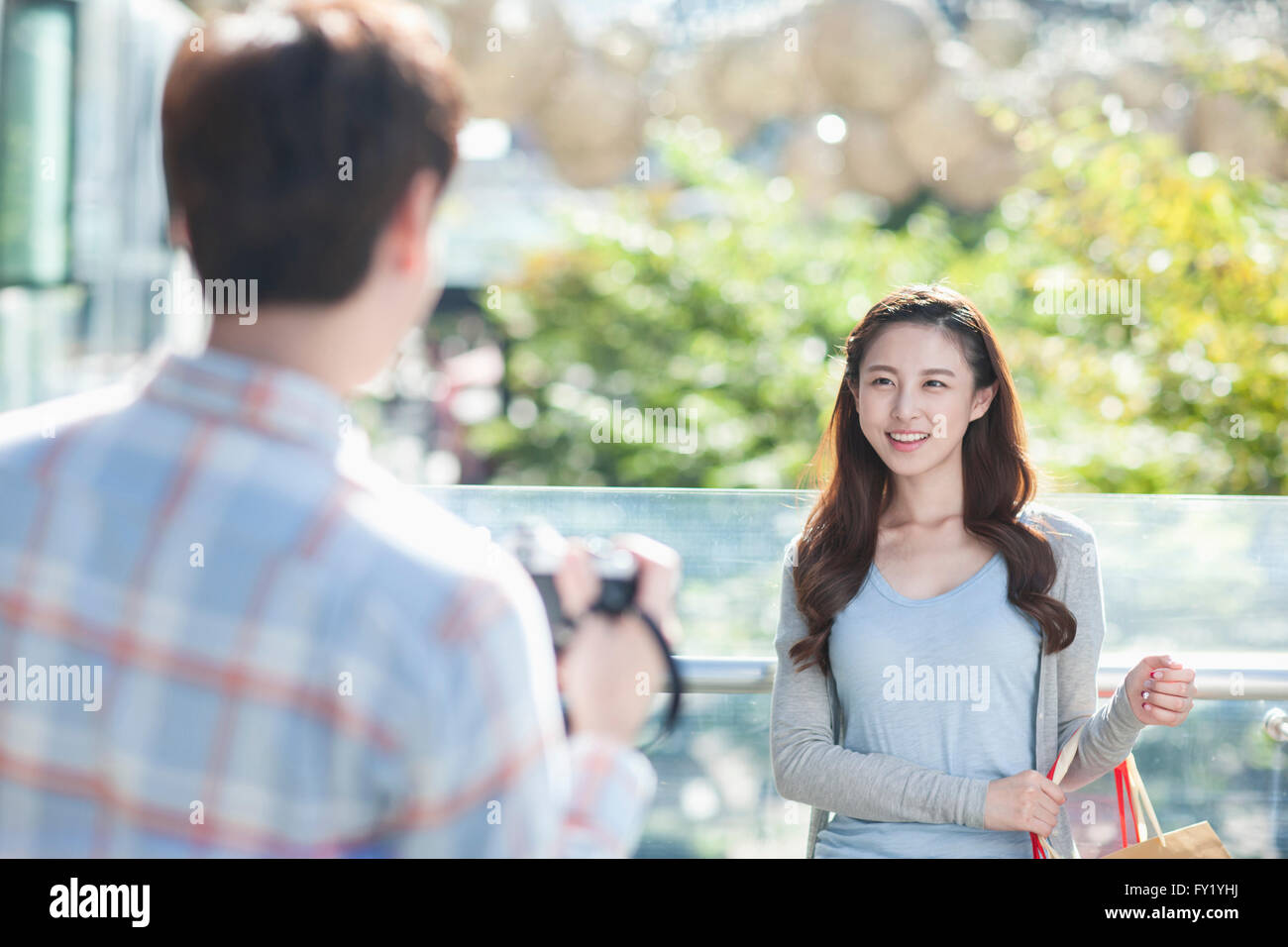 Woman with shopping bags smiling vers l'appareil photo tenu par un homme à l'extérieur Banque D'Images