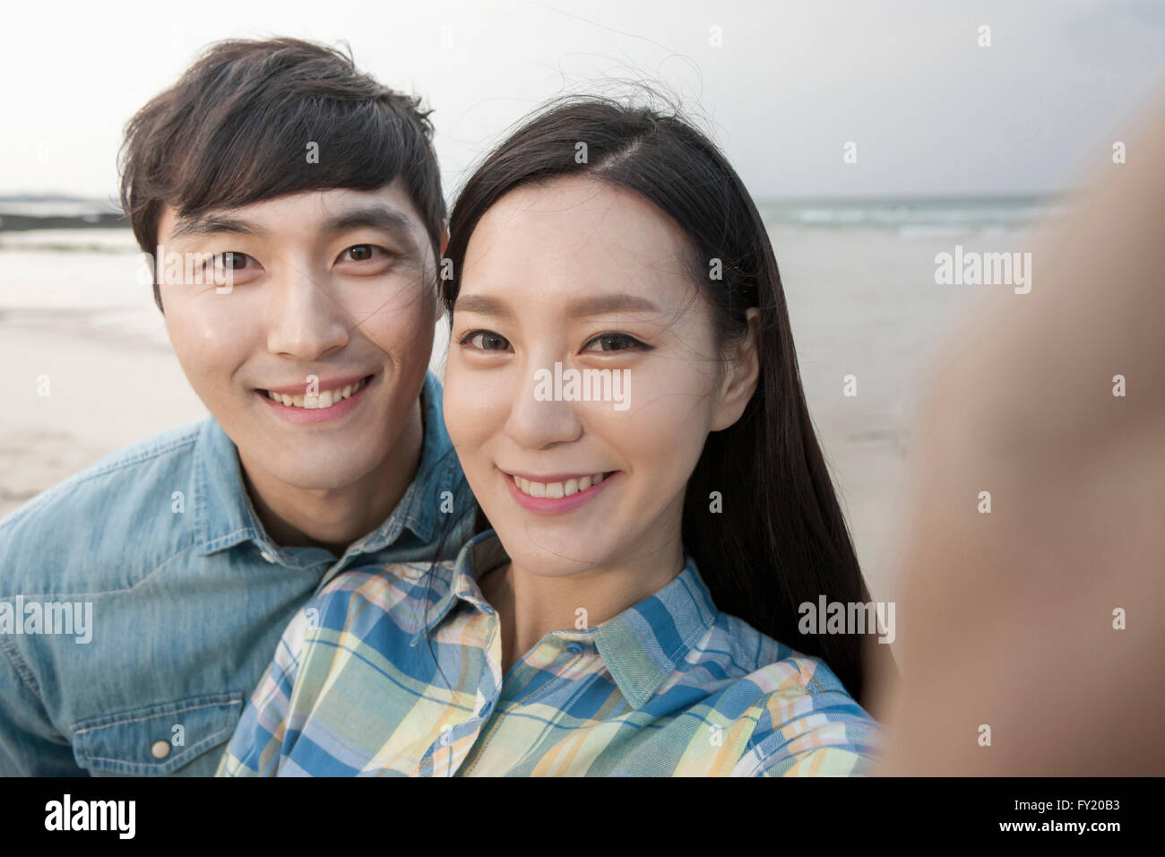 Couple smiling at the camera at the beach Banque D'Images