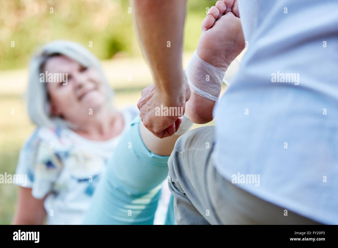 Homme donne les premiers soins à l'aide d'une femme senior avec une entorse à la cheville Banque D'Images