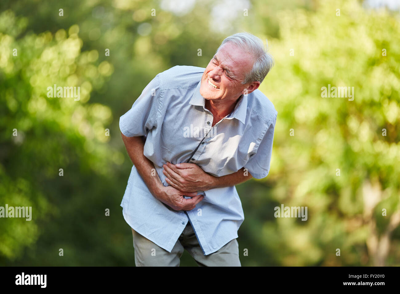 Vieil homme avec estomac toching son estomac dans la nature Banque D'Images