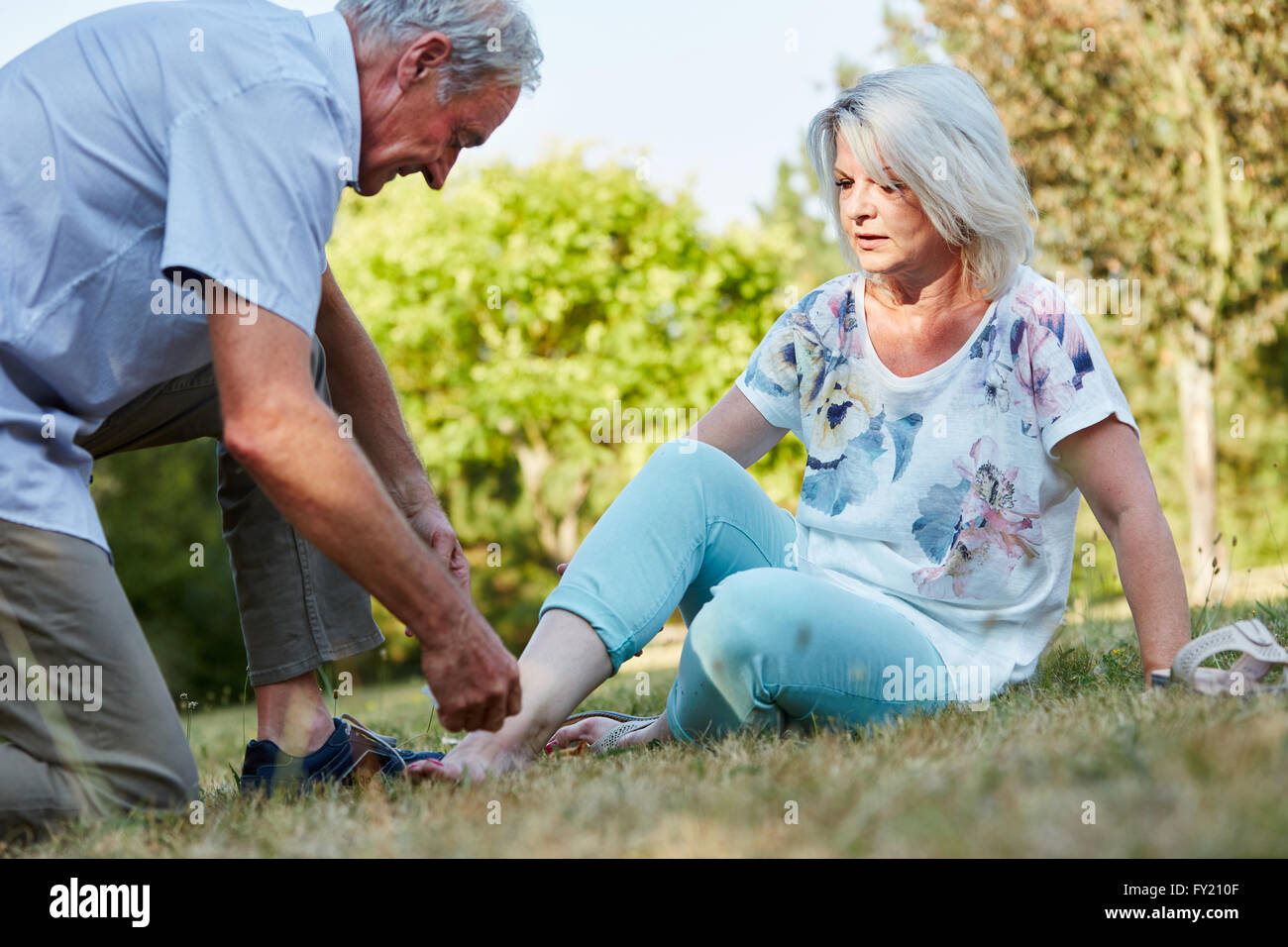 Vieil homme femme aide avec l'entorse de la cheville dans la nature Banque D'Images