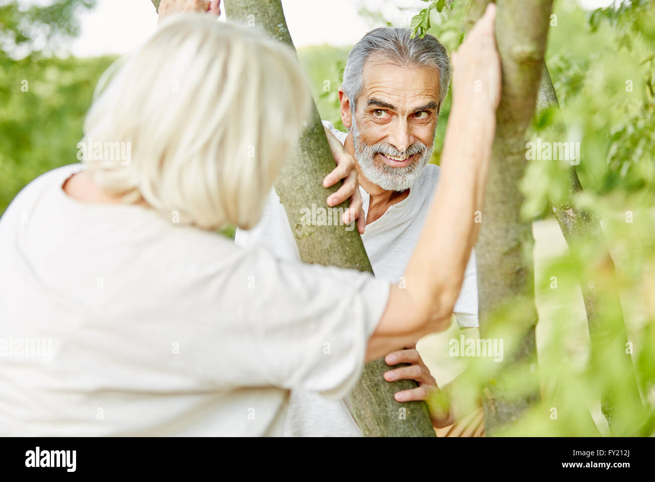 Senior couple flirting et joue à cache-cache en été dans la nature Banque D'Images