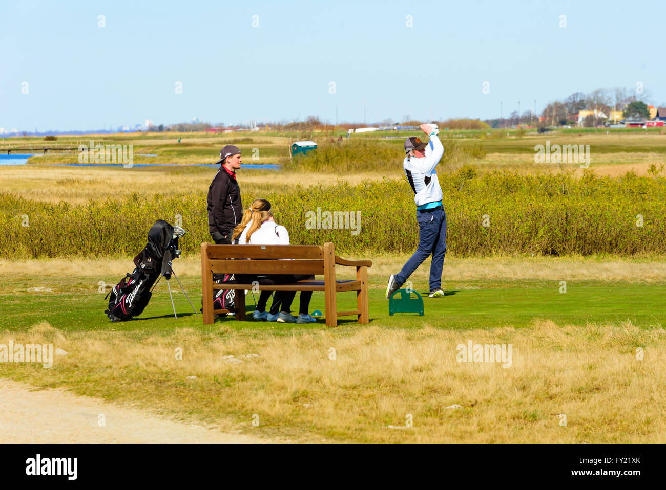 Skanor, Suède - 11 Avril 2016 : quatre jeunes golfeurs à jouer quelques tee golf. Un mâle alors que le swing d'autres donnent sur l'attente fo Banque D'Images