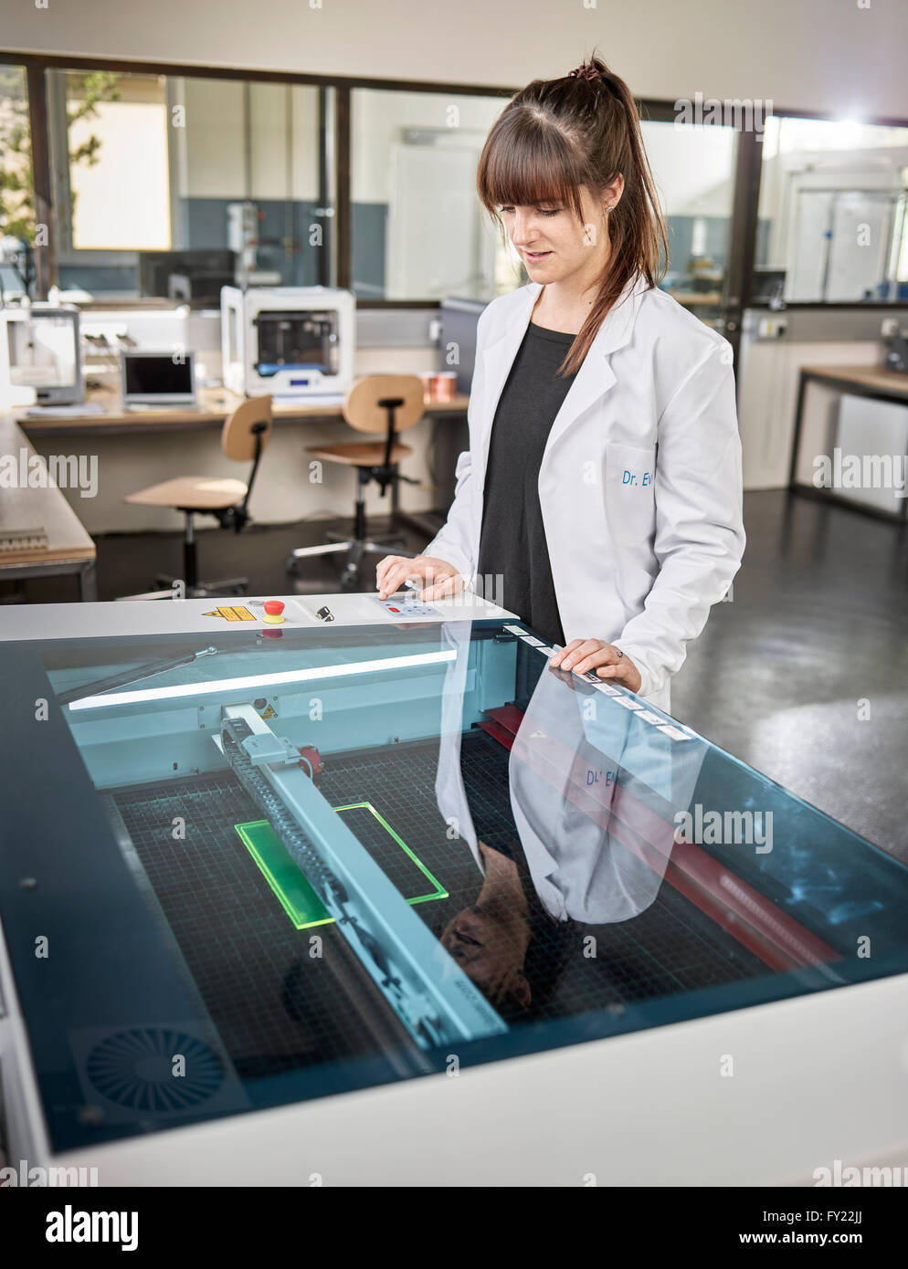Technicien de sexe féminin, de 20 à 25 ans, avec un sarrau blanc, à l'aide d'un cutter laser dans un laboratoire électronique, Wattens Banque D'Images