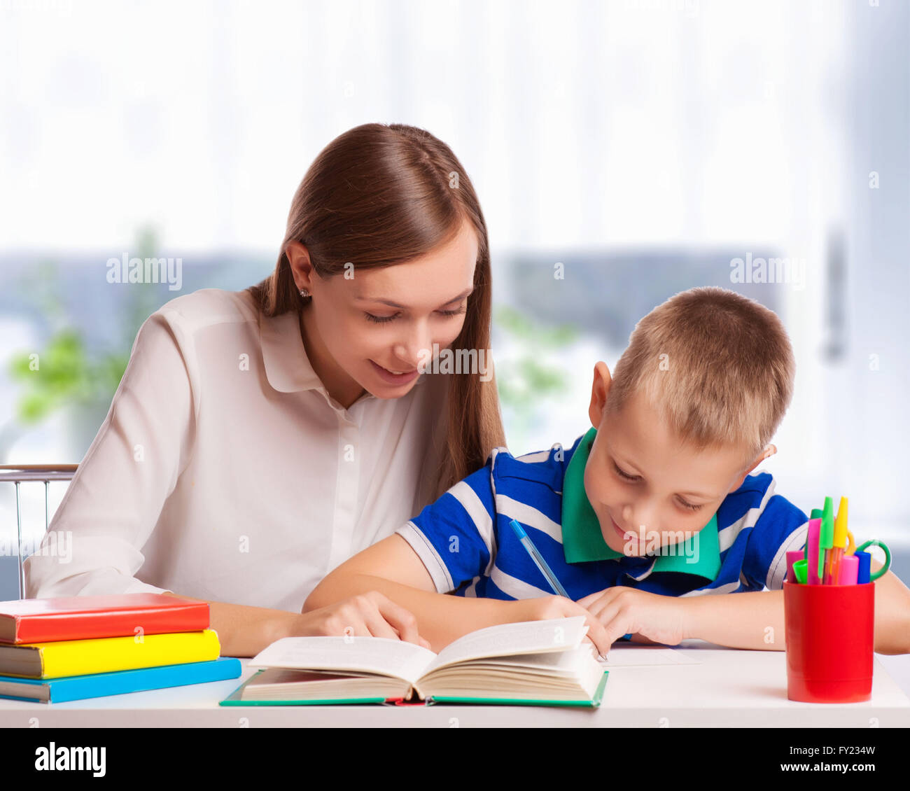 Mother helping son with Homework at table Banque D'Images