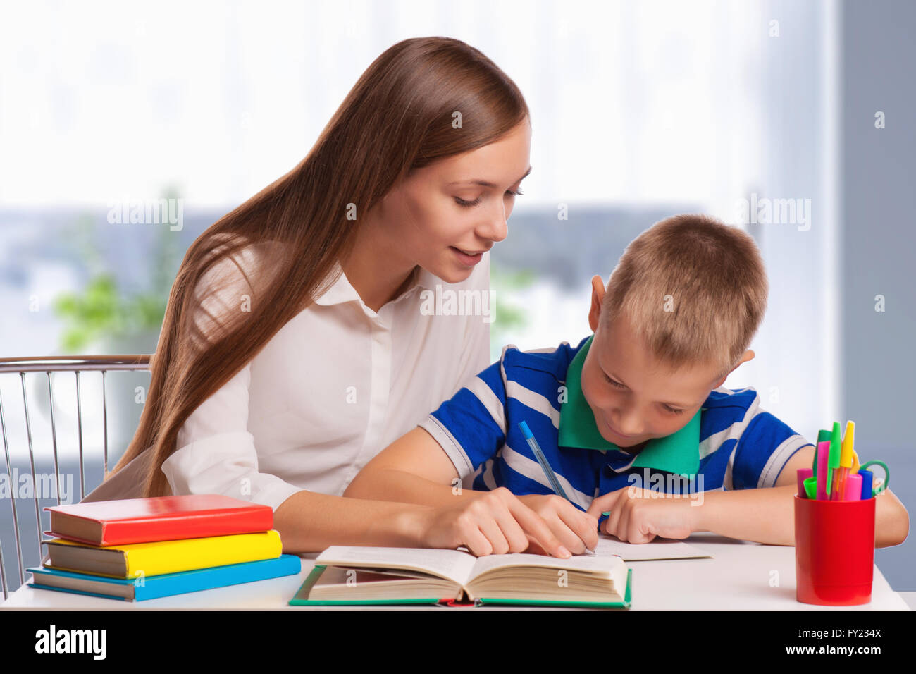 Mother helping son with Homework at table Banque D'Images