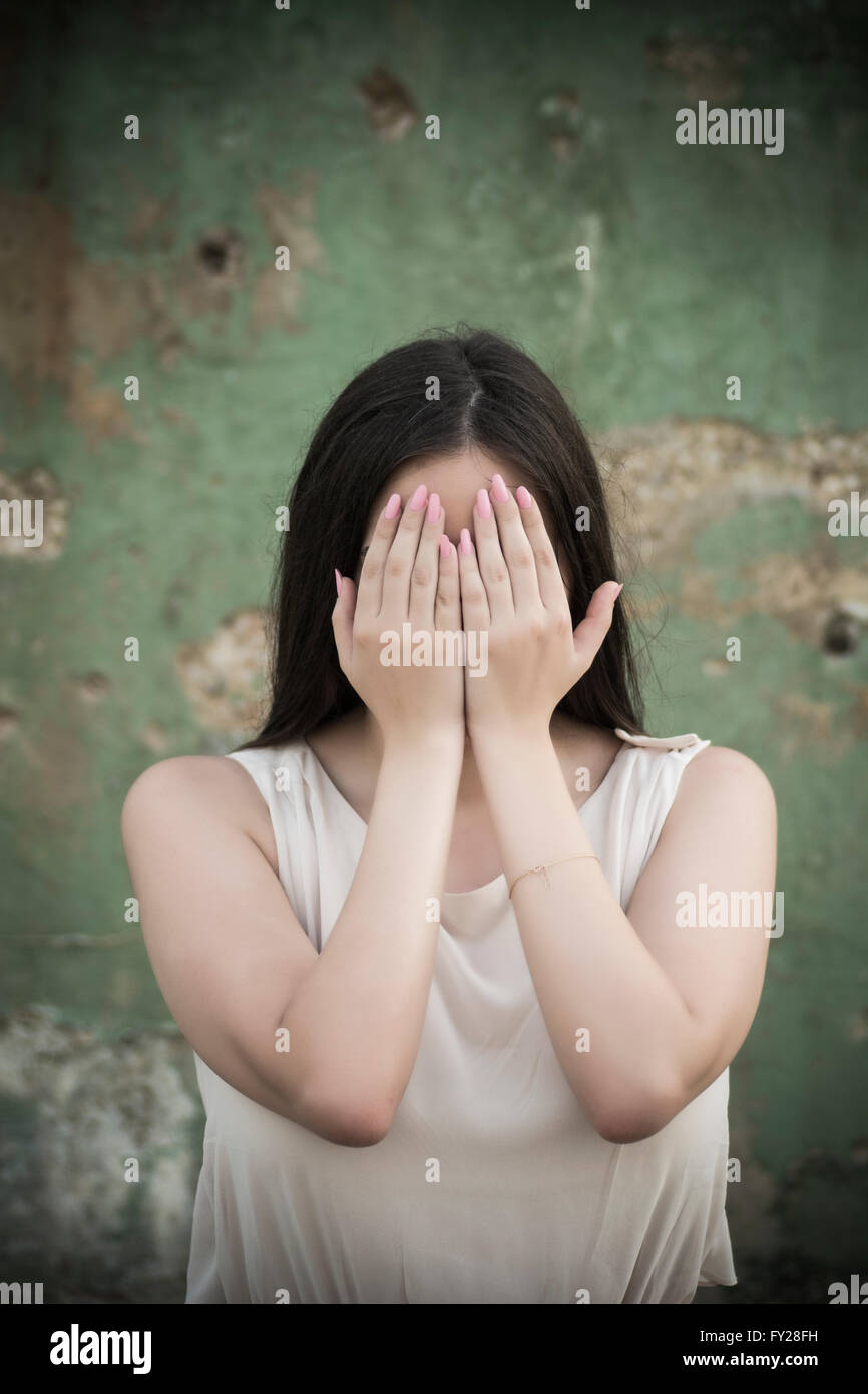 Jeune femme effrayée de se cacher le visage avec les mains Banque D'Images