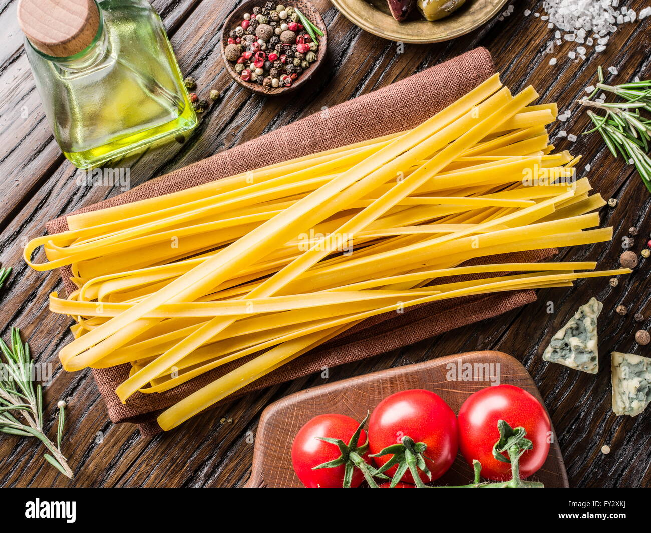 Ingrédients pâtes. Les tomates cerise, les pâtes spaghetti, de romarin et d'épices sur la table en bois. Banque D'Images