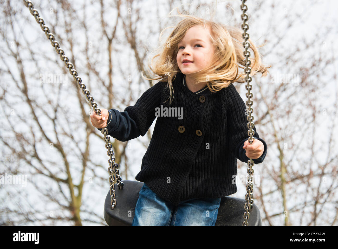 Petit enfant fille blonde s'amusant sur une balançoire à l'extérieur. Jeux d'été. Haut fille se balançant Banque D'Images