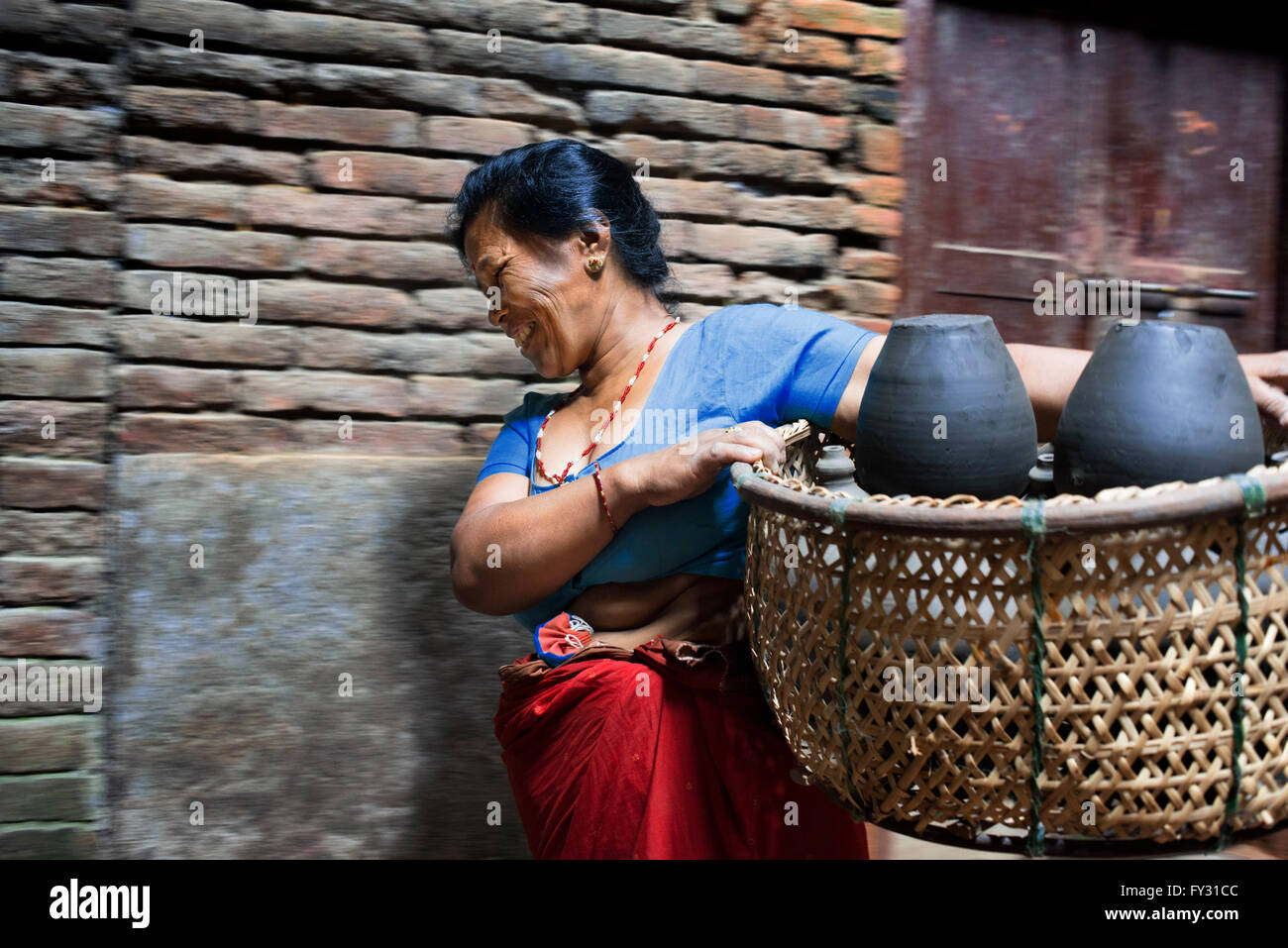 Femme locale transports pots pour sécher au soleil, Place Pottery, Bhaktapur, Népal Banque D'Images