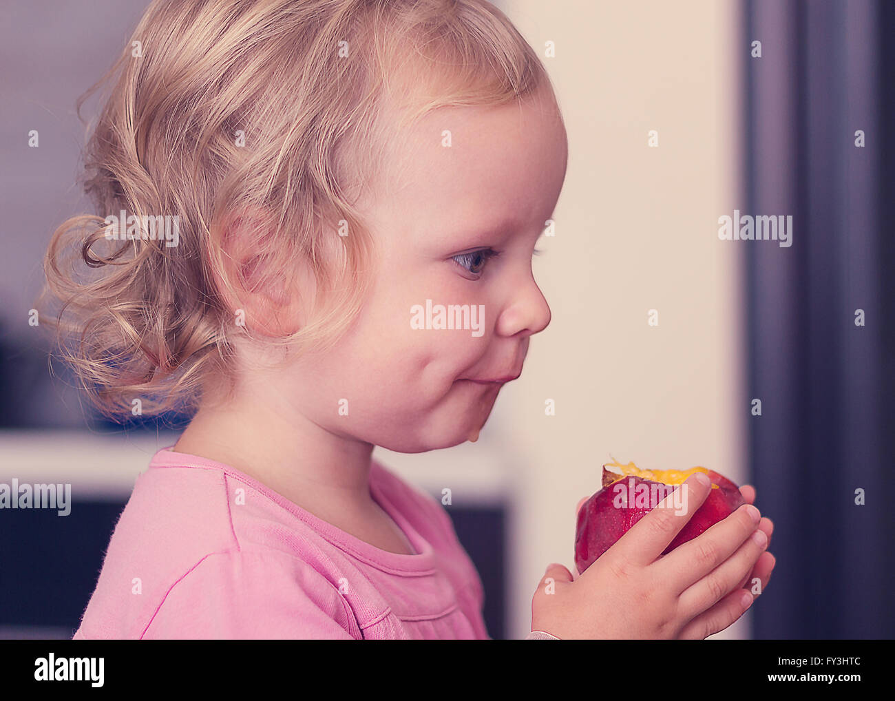 Funny little girl (2 ans) Eat a Peach. Focus sélectif. Banque D'Images