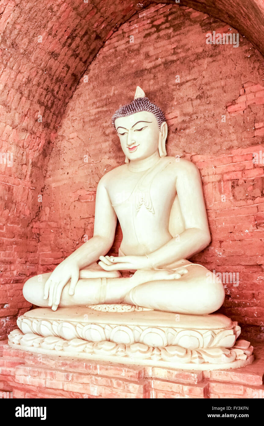 Style birman Bouddha blanc en face de pierre mur de brique pleine méditant dans la posture du lotus Banque D'Images