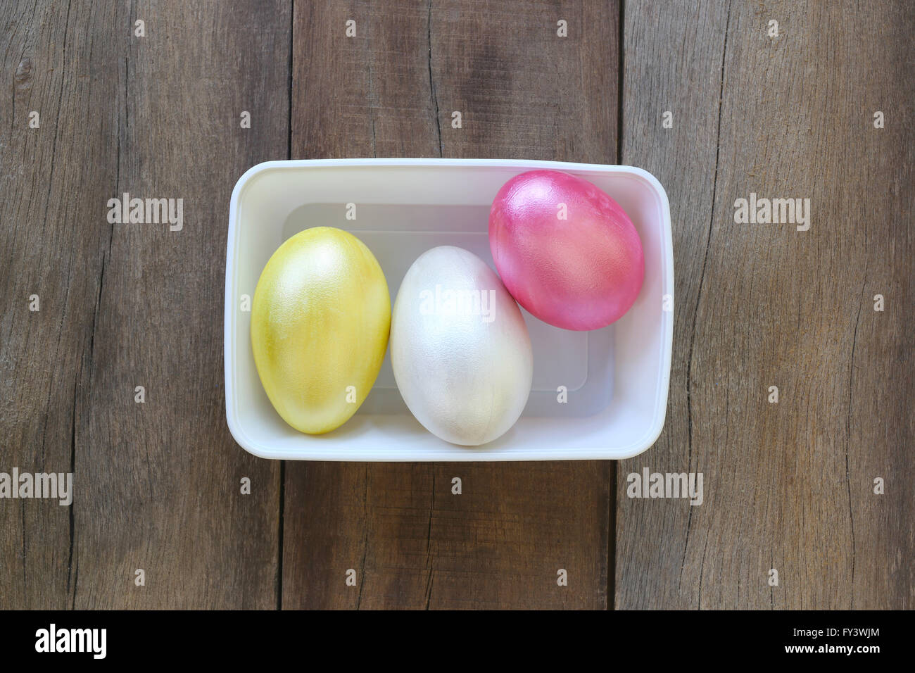 Œuf de Pâques une variété de couleurs dans un bol en plastique sur fond sombre. Banque D'Images