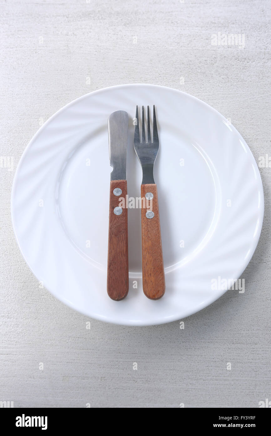 Plat blanc avec un couteau et fourchette est placé sur la table. Banque D'Images
