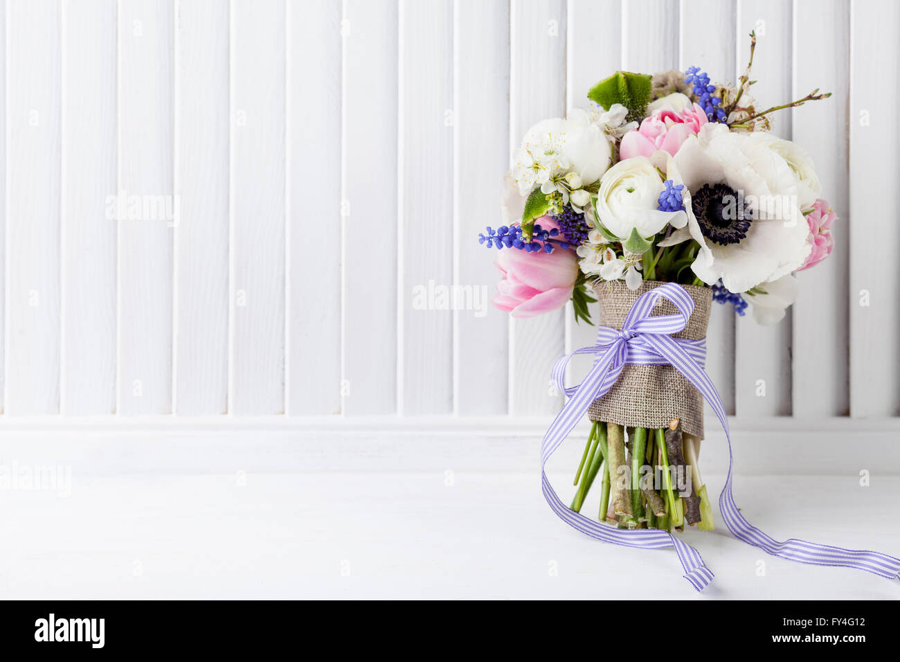 Bouquet de tulipes roses, violettes, muscaris anémones blanc, violet et blanc veronica buttercup avec ruban violet sur whit Banque D'Images